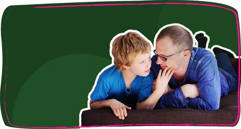 A father and his young son lying down together, smiling and talking